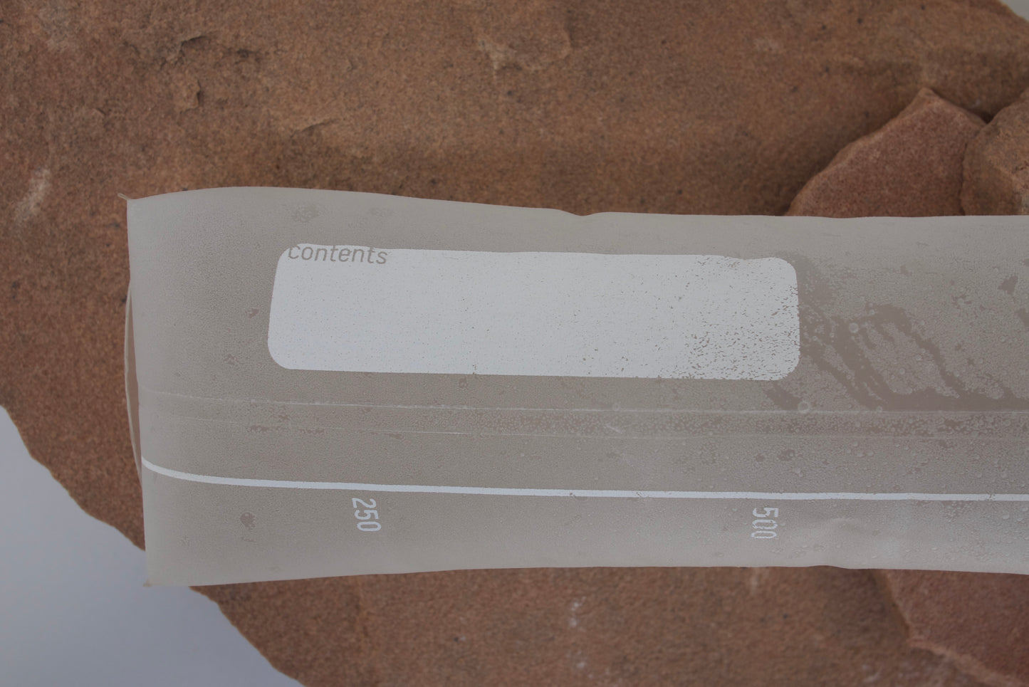 Clear plastic strip with measurement markings on a brown textured background
